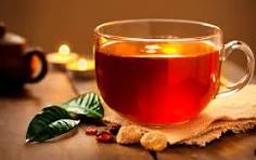 استکان چای در کنار برگ سیز چای